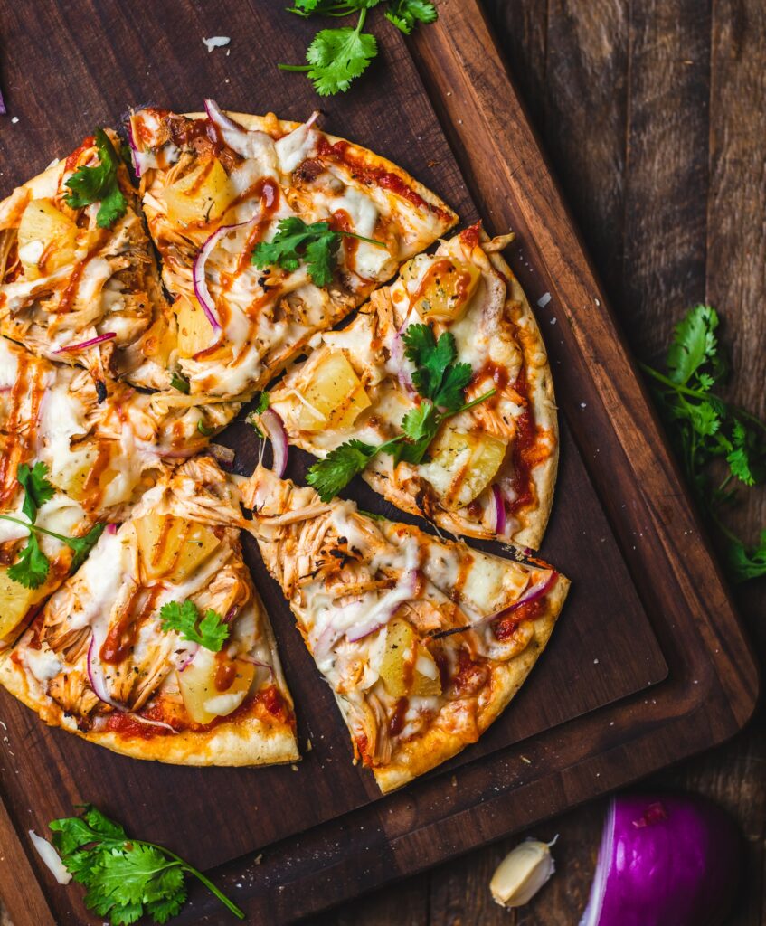 A pizza with seasoning on a wooden platter on a brown table